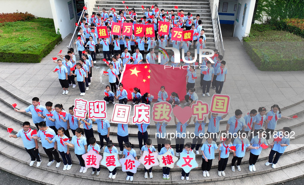 Primary school students pose for a photo with the national flag to celebrate the 75th anniversary of the founding of China in Taicang, Jiang...