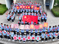 Primary school students pose for a photo with the national flag to celebrate the 75th anniversary of the founding of China in Taicang, Jiang...