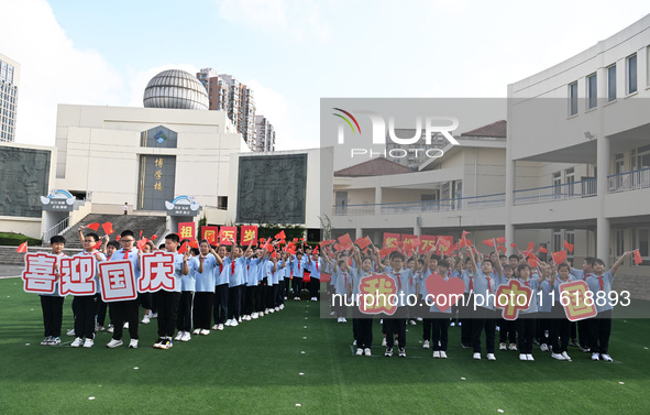 Primary school students pose for a photo with the national flag to celebrate the 75th anniversary of the founding of China in Taicang, Jiang...