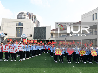 Primary school students pose for a photo with the national flag to celebrate the 75th anniversary of the founding of China in Taicang, Jiang...