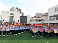 Primary school students pose for a photo with the national flag to celebrate the 75th anniversary of the founding of China in Taicang, Jiang...