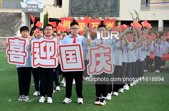 Primary school students pose for a photo with the national flag to celebrate the 75th anniversary of the founding of China in Taicang, Jiang...