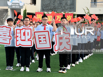 Primary school students pose for a photo with the national flag to celebrate the 75th anniversary of the founding of China in Taicang, Jiang...