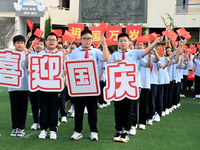 Primary school students pose for a photo with the national flag to celebrate the 75th anniversary of the founding of China in Taicang, Jiang...