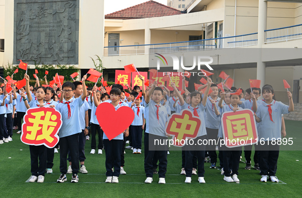 Primary school students pose for a photo with the national flag to celebrate the 75th anniversary of the founding of China in Taicang, Jiang...