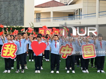 Primary school students pose for a photo with the national flag to celebrate the 75th anniversary of the founding of China in Taicang, Jiang...