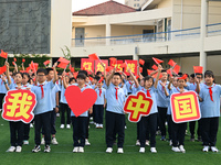 Primary school students pose for a photo with the national flag to celebrate the 75th anniversary of the founding of China in Taicang, Jiang...