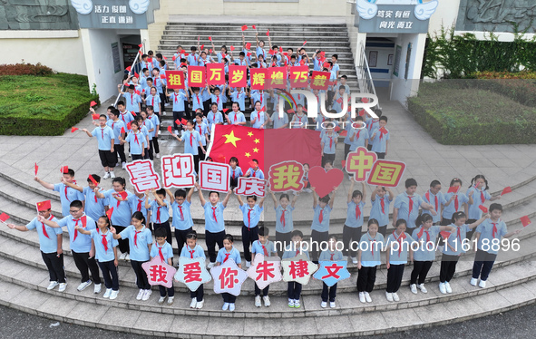 Primary school students pose for a photo with the national flag to celebrate the 75th anniversary of the founding of China in Taicang, Jiang...