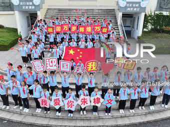 Primary school students pose for a photo with the national flag to celebrate the 75th anniversary of the founding of China in Taicang, Jiang...