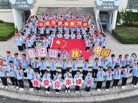 Primary school students pose for a photo with the national flag to celebrate the 75th anniversary of the founding of China in Taicang, Jiang...