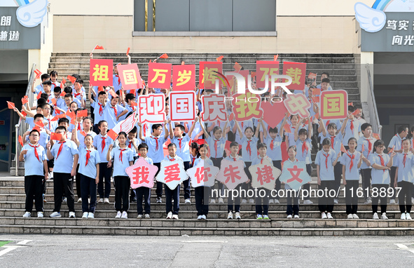 Primary school students pose for a photo with the national flag to celebrate the 75th anniversary of the founding of China in Taicang, Jiang...