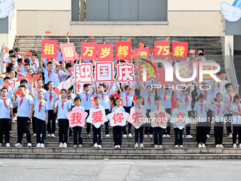 Primary school students pose for a photo with the national flag to celebrate the 75th anniversary of the founding of China in Taicang, Jiang...