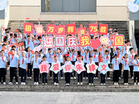 Primary school students pose for a photo with the national flag to celebrate the 75th anniversary of the founding of China in Taicang, Jiang...