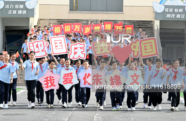 Primary school students pose for a photo with the national flag to celebrate the 75th anniversary of the founding of China in Taicang, Jiang...