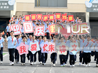 Primary school students pose for a photo with the national flag to celebrate the 75th anniversary of the founding of China in Taicang, Jiang...