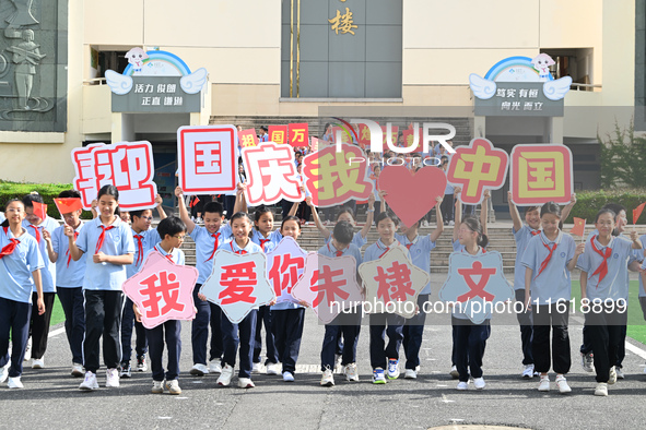 Primary school students pose for a photo with the national flag to celebrate the 75th anniversary of the founding of China in Taicang, Jiang...