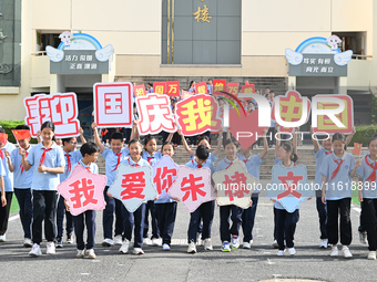 Primary school students pose for a photo with the national flag to celebrate the 75th anniversary of the founding of China in Taicang, Jiang...