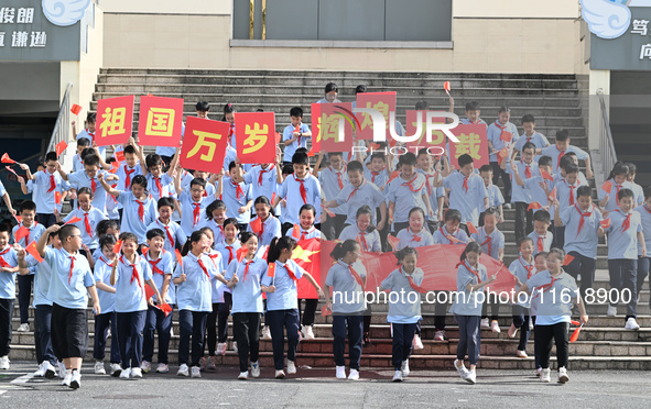 Primary school students pose for a photo with the national flag to celebrate the 75th anniversary of the founding of China in Taicang, Jiang...