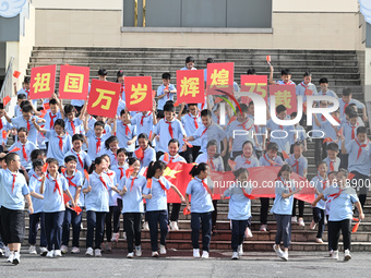 Primary school students pose for a photo with the national flag to celebrate the 75th anniversary of the founding of China in Taicang, Jiang...