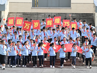 Primary school students pose for a photo with the national flag to celebrate the 75th anniversary of the founding of China in Taicang, Jiang...