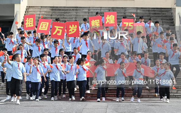 Primary school students pose for a photo with the national flag to celebrate the 75th anniversary of the founding of China in Taicang, Jiang...