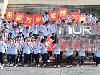 Primary school students pose for a photo with the national flag to celebrate the 75th anniversary of the founding of China in Taicang, Jiang...