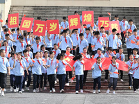 Primary school students pose for a photo with the national flag to celebrate the 75th anniversary of the founding of China in Taicang, Jiang...