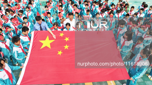 A prosecutor explains national flag knowledge to children at Qianhe Primary School in Situi Town, Guanyun County, Lianyungang City, Jiangsu...