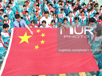 A prosecutor explains national flag knowledge to children at Qianhe Primary School in Situi Town, Guanyun County, Lianyungang City, Jiangsu...