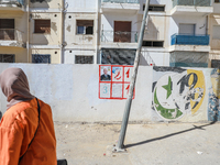 A woman walks past an election poster of presidential candidate Kais Saied stuck on a wall along a street in Ariana, Tunisia, on September 2...