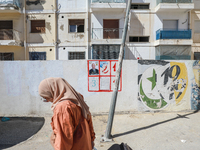 A woman walks past an election poster of presidential candidate Kais Saied stuck on a wall along a street in Ariana, Tunisia, on September 2...