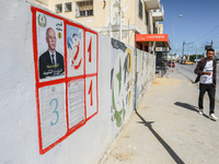 A young man walks past an election poster of presidential candidate Kais Saied stuck on a wall along a street in Ariana, Tunisia, on Septemb...