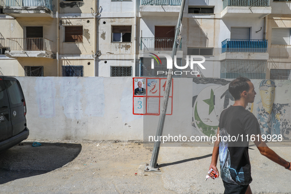 A young man walks past an election poster of presidential candidate Kais Saied stuck on a wall along a street in Ariana, Tunisia, on Septemb...