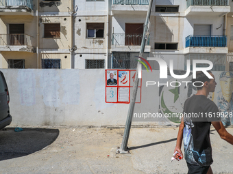 A young man walks past an election poster of presidential candidate Kais Saied stuck on a wall along a street in Ariana, Tunisia, on Septemb...