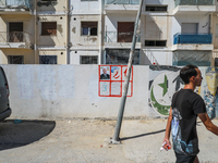 A young man walks past an election poster of presidential candidate Kais Saied stuck on a wall along a street in Ariana, Tunisia, on Septemb...