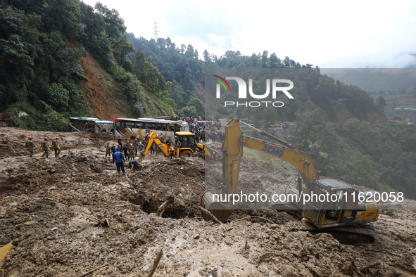 Excavators comb through the mud in search of bodies of passengers believed to be buried in the landslide that covers multiple vehicles at Jh...