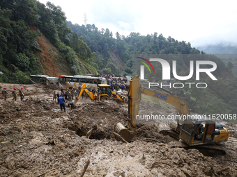 Excavators comb through the mud in search of bodies of passengers believed to be buried in the landslide that covers multiple vehicles at Jh...