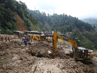 Excavators comb through the mud in search of bodies of passengers believed to be buried in the landslide that covers multiple vehicles at Jh...