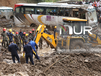 Excavators comb through the mud in search of bodies of passengers believed to be buried in the landslide that covers multiple vehicles at Jh...