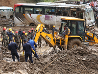 Excavators comb through the mud in search of bodies of passengers believed to be buried in the landslide that covers multiple vehicles at Jh...