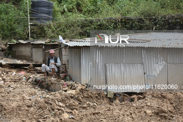 A Nepali man rests next to a tin shelter damaged by a landslide in Dhading district of Central Nepal on September 29, 2024. At least 35 peop...