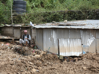 A Nepali man rests next to a tin shelter damaged by a landslide in Dhading district of Central Nepal on September 29, 2024. At least 35 peop...