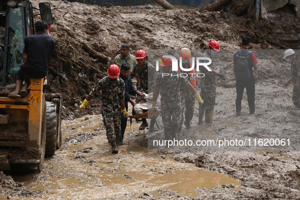 Nepal Army personnel carry the body of a passenger retrieved from the landslide site in Jhyaple Khola in Dhading district of Central Nepal o...