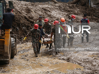 Nepal Army personnel carry the body of a passenger retrieved from the landslide site in Jhyaple Khola in Dhading district of Central Nepal o...