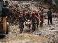 Nepal Army personnel carry the body of a passenger retrieved from the landslide site in Jhyaple Khola in Dhading district of Central Nepal o...