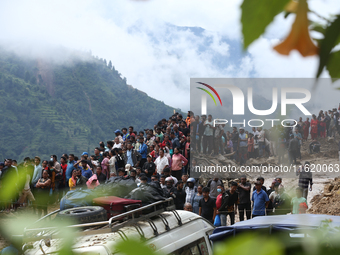 Locals and relatives of the missing passengers gather at Jhyaple Khola in Dhading District, Nepal, on September 29, 2024, as the search oper...