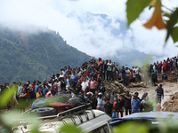 Locals and relatives of the missing passengers gather at Jhyaple Khola in Dhading District, Nepal, on September 29, 2024, as the search oper...