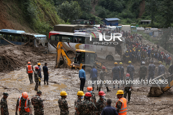 Excavators comb through the mud in search of bodies of passengers believed to be buried in the landslide that covers multiple vehicles at Jh...