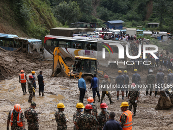 Excavators comb through the mud in search of bodies of passengers believed to be buried in the landslide that covers multiple vehicles at Jh...