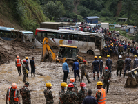 Excavators comb through the mud in search of bodies of passengers believed to be buried in the landslide that covers multiple vehicles at Jh...